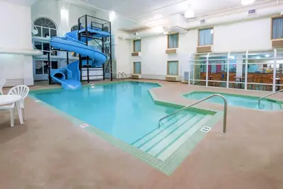 a large swimming pool with a slide in a building at Super 8 by Wyndham Three Hills AB in Three Hills