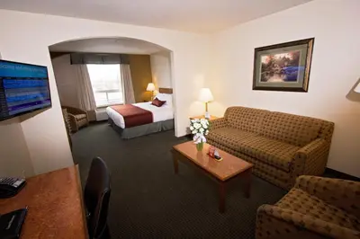 a hotel room with a couch and a bed at Service Plus Inns & Suites Drayton Valley in Drayton Valley