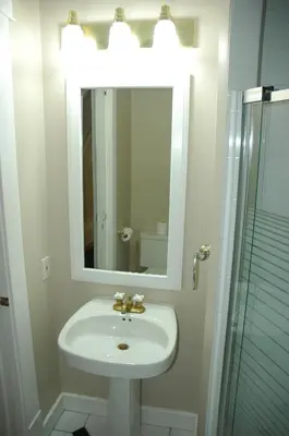 a bathroom with a sink and a mirror and a shower at Windsor Guest House in Vancouver