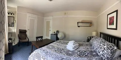 a bedroom with a bed and a desk and a chair at Windsor Guest House in Vancouver