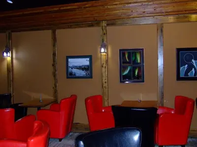 a restaurant with red chairs and tables and pictures on the wall at The Yukon Inn in Whitehorse