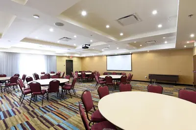 a conference room with tables and chairs and a screen at Fairfield Inn & Suites by Marriott Vernon in Vernon