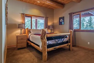 a bedroom with a bed and a desk and windows at Spirit Lodge at Silverstar in Vernon