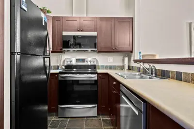 a kitchen with wooden cabinets and a black refrigerator at Stones Throw #26 By Bear Country in Sun Peaks