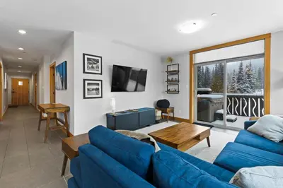 a living room with blue couches and a tv at Kookaburra Lodge #203 By Bear Country in Sun Peaks