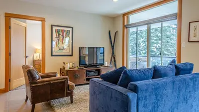 a living room with a blue couch and a tv at Kookaburra Lodge #303 By Bear Country in Sun Peaks
