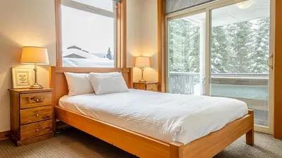a bedroom with a bed and a large window at Kookaburra Lodge #303 By Bear Country in Sun Peaks