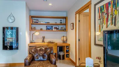 a living room with a leather chair and a television at Kookaburra Lodge #303 By Bear Country in Sun Peaks