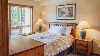 a bedroom with a bed and two lamps and a window at Fireside Lodge #419 By Bear Country in Sun Peaks