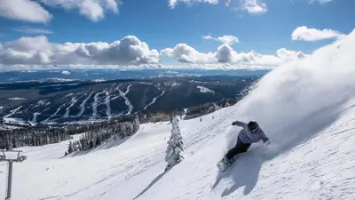 a man riding a snowboard down a snow covered slope at Fireside Lodge #413 By Bear Country in Sun Peaks