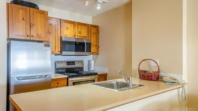 a kitchen with stainless steel appliances and wooden cabinets at Fireside Lodge #413 By Bear Country in Sun Peaks