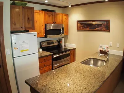 a kitchen with a white refrigerator and a sink at Fireside Lodge #409 By Bear Country in Sun Peaks