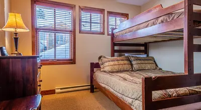 a bedroom with a bunk bed and windows at Woodhaven #36 By Bear Country in Sun Peaks