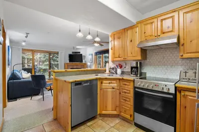 a kitchen with wooden cabinets and a stove top oven at Snow Creek Village #37 By Bear Country in Sun Peaks
