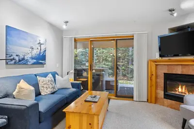 a living room with a blue couch and a fireplace at Snow Creek Village #37 By Bear Country in Sun Peaks