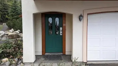 a green door on a house with a garage at Timberline Village #14 By Bear Country in Sun Peaks