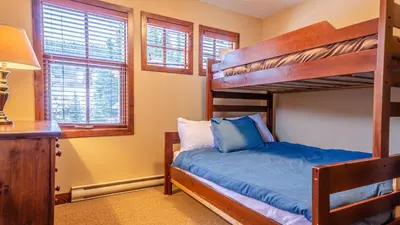 a bedroom with a bunk bed and two windows at Woodhaven #32 By Bear Country in Sun Peaks