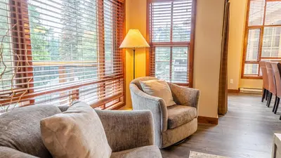 a living room with a couch and chairs and windows at Woodhaven #32 By Bear Country in Sun Peaks