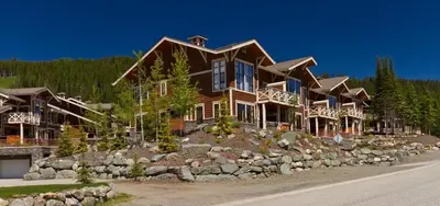 a large wooden house on a hill with trees at Stones Throw #11 By Bear Country in Sun Peaks
