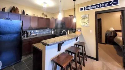 a kitchen with a black refrigerator and wooden cabinets at Stones Throw #38 By Bear Country in Sun Peaks