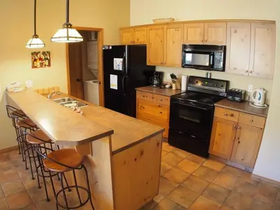 a kitchen with wooden cabinets and a black refrigerator at Crystal Forest #72 By Bear Country in Sun Peaks