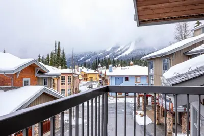 a view from a balcony of a town with snow at Trappers Landing #11 By Bear Country in Sun Peaks