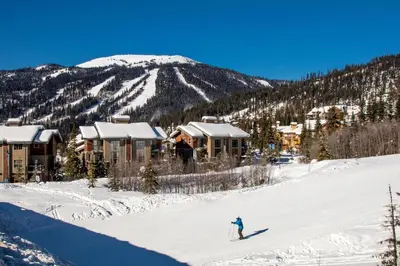 a person is skiing down a snow covered slope at Trappers Landing #11 By Bear Country in Sun Peaks