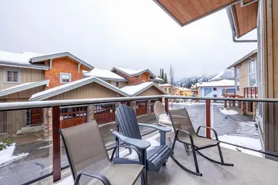 a balcony with chairs and a table and snow at Trappers Landing #11 By Bear Country in Sun Peaks