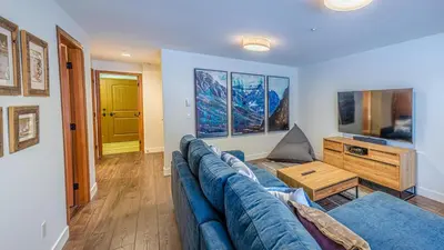 a living room with a blue couch and a television at Trails Edge #25 By Bear Country in Sun Peaks