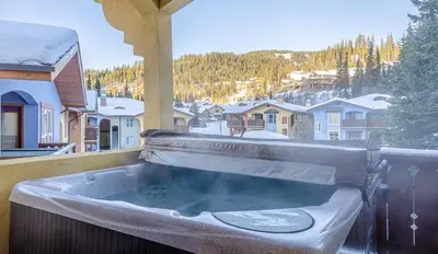 a hot tub on a balcony with a view of a mountain at Crystal Forest #54 By Bear Country in Sun Peaks