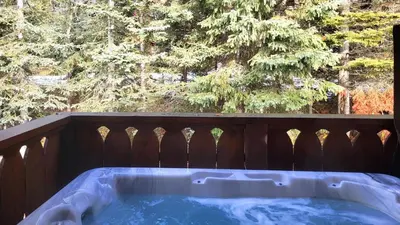a hot tub on a deck with a wooden fence at Crystal Forest #11 By Bear Country in Sun Peaks