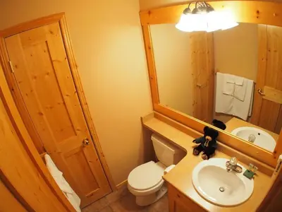 a bathroom with a toilet and a sink and a mirror at Crystal Forest #07 By Bear Country in Sun Peaks