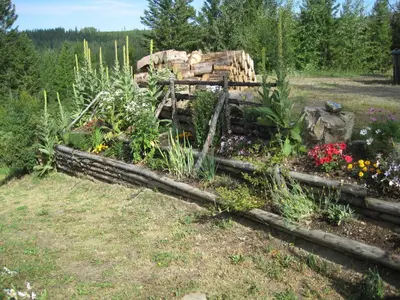 a garden with flowers and a pile of logs at Wild Nature B&B in Kelowna