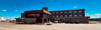 a building with a car parked in front of it at Camrose Le Chateau Hotel in Camrose