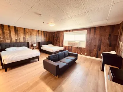 a room with two beds and a couch and a bed at Camrose Le Chateau Hotel in Camrose