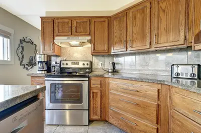 a kitchen with wooden cabinets and stainless steel appliances at Rodee Homestay in West Kelowna