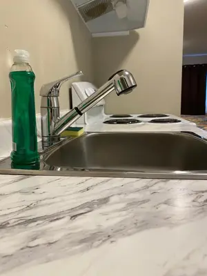 a kitchen sink with a green bottle on it at Imperial Motel in One Hundred Mile House
