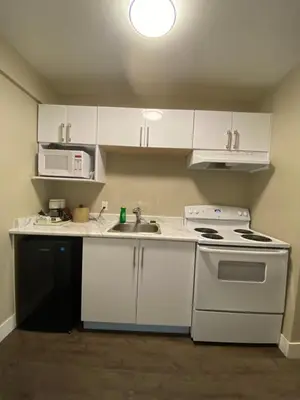 a small kitchen with white cabinets and a sink at Imperial Motel in One Hundred Mile House