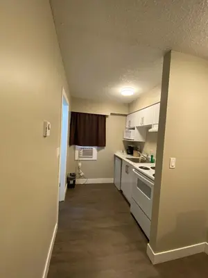 a small kitchen with white cabinets and a stove at Imperial Motel in One Hundred Mile House