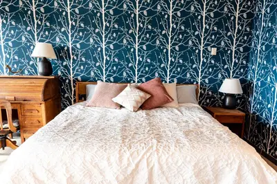 a bedroom with a bed with a blue and white wallpaper at Pacific Soul Eco-Luxe Vacation Home in Ucluelet