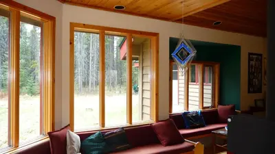 a living room with a couch and windows at HI Castle Mountain - Hostel in Castle Junction