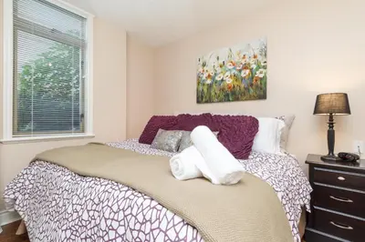 a bedroom with a bed and a painting on the wall at 5 Min Walk To Famous Victoria Inner Harbour And Empress Hotel in Victoria