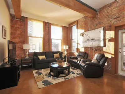 a living room with leather furniture and a brick wall at Gorgeous Luxury 2 Bedroom 2 Bath Condo In Old Town Victoria in Victoria