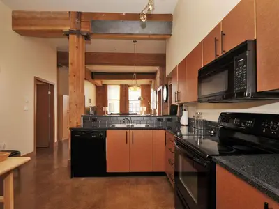a large kitchen with black appliances and wooden cabinets at Gorgeous Luxury 2 Bedroom 2 Bath Condo In Old Town Victoria in Victoria