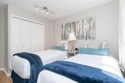 two beds in a white room with blue sheets at Deluxe 2 Bed 2 Bath And 5 Min Walk To Downtown And Seawalk in Victoria