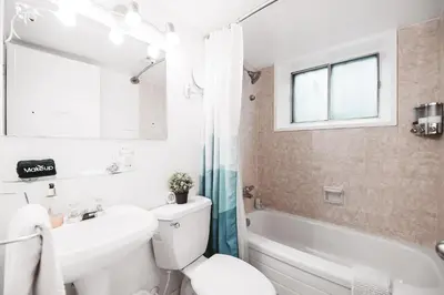 a bathroom with a white toilet and a tub and a sink at Along River Ridge in Calgary