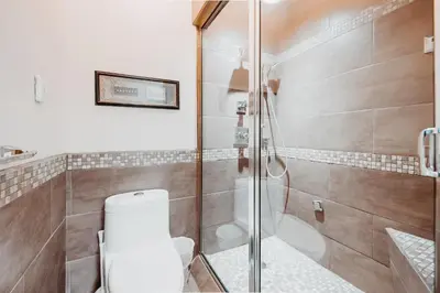 a bathroom with a glass shower with a toilet at Along River Ridge in Calgary