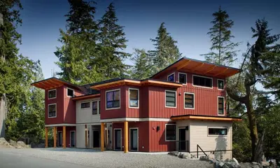 a red and white house with trees in the background at The Cabins at Terrace Beach in Ucluelet