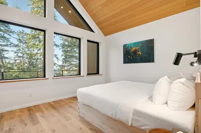a bedroom with a white bed and windows at The Cabins at Terrace Beach in Ucluelet