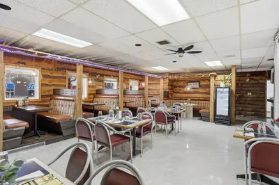 a restaurant with tables and chairs and wooden walls at Lillooet Hotel Victoria in Lillooet